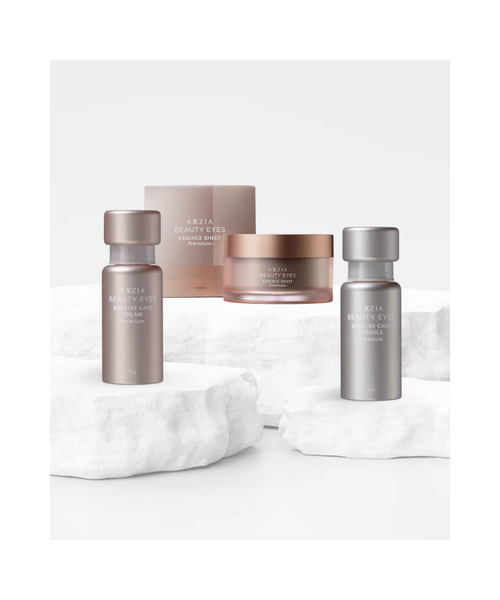 AXXZIA Ritual of Complete Eye Regeneration – trzy produkty do pielęgnacji okolic oczu na marmurowym podium, Beauty Eyes Essence Sheet Premium+, Routine Care Essence i Cream Premium